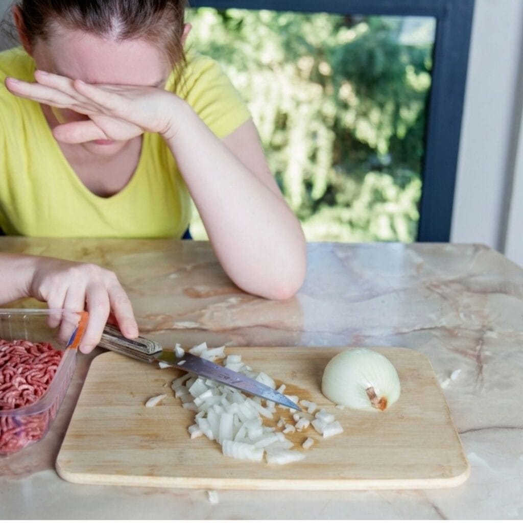 persona picando cebolla en la cocina de su casa en Chile con los ojos entrecerrados