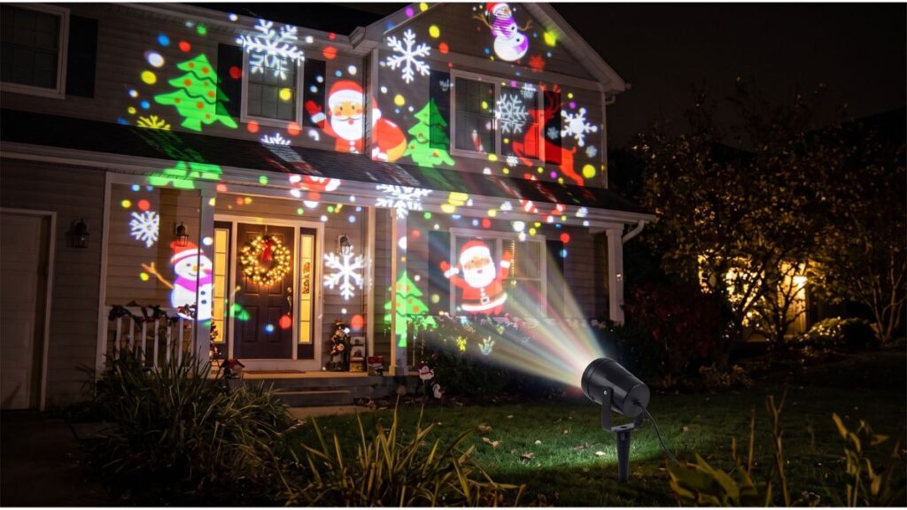 Casa de dos pisos decorada e iluminada de noche para Navidad con un proyector LED de exterior desde el antejardín